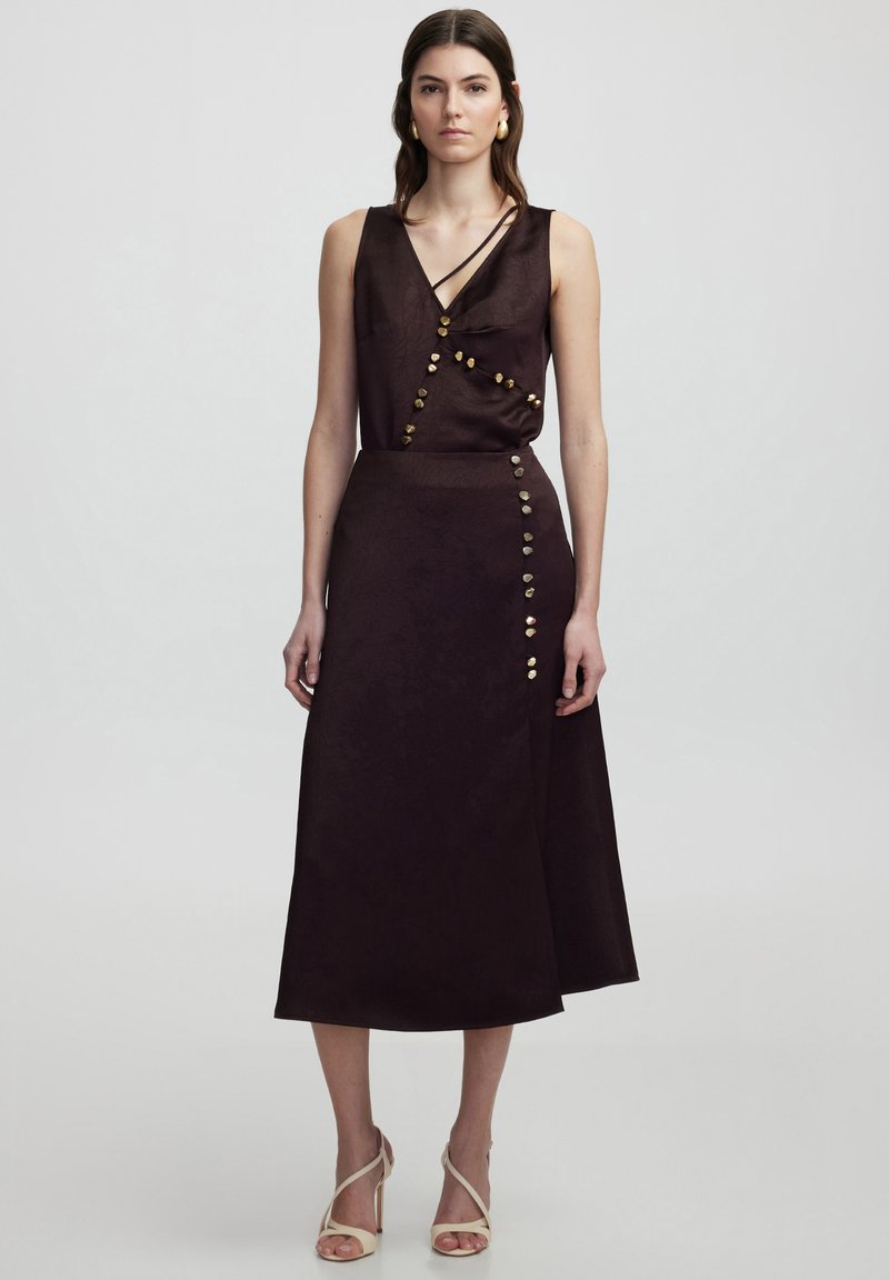 Dunkellila Kleid mit anliegendem Oberteil und ausgestellt Rock, mit goldenen Knopfakzenten an der Seite und einer strukturierten Stoffoberfläche.