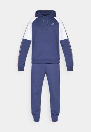 Donkerblauwe trainingsset met sweatshirt en joggingbroek. De hoodie heeft witte mouwen, een verstelbare trekkoord, een voorzak en een logo. Zachte stoftextuur.