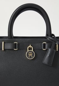 Sort læder håndtaske med tekstureret overflade, dobbelte top håndtag, hardware i guld-tone, låseaccent og brandemblem vedhæftet.