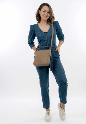 Sac en bandoulière en cuir tan avec un logo triangulaire, associé à une combinaison en denim avec un décolleté en V, des manches bouffantes et une taille ceinturée.