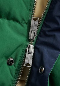Green and navy quilted jacket with a double zipper, metallic hardware, and a snap button. Smooth fabric with a shiny finish.
