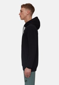 Sweat à capuche noir avec une poche kangourou, cordon de serrage ajustable et logo sur la poitrine. Il comprend des manches longues et une coupe décontractée.