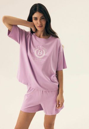 Helle lila Freizeitkleidung bestehend aus einem lässigen T-Shirt mit kurzen Ärmeln und einem Logo sowie passenden Shorts, hergestellt aus weichem, atmungsaktivem Material.