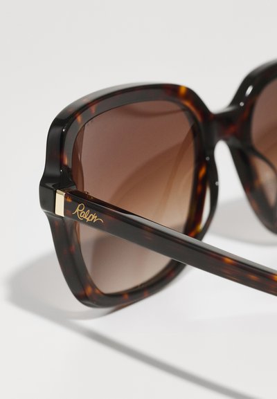 Schildpatt-Sonnenbrille mit dickem Rahmen, braunen verlaufenden Gläsern, goldenen Akzenten an den Bügeln und dem Schriftzug "Ralph" in Schreibschrift an der Seite.