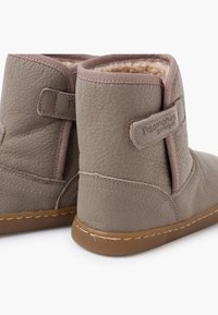 Bruine leren enkellaarsjes met een gestructureerde afwerking, zachte voering en een lichtbruine rubberen zool. Voorzien van een klittenbandsluiting en decoratieve stiksels.