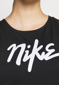 Haut sans manches noir avec un col rond et un logo "Nike" blanc imprimé sur le devant. Le tissu semble lisse et ajusté.