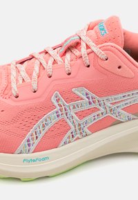 Chaussure de sport rose avec un dessus en maille texturée, des accents brodés avec des fils multicolores et une semelle en mousse de couleur claire.