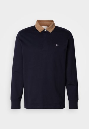 Laivastonsininen pitkähihaisen polo-paita, jossa on vaaleanruskea corduroy-kenttä, kahden napin placket ja pieni logo vasemmassa rinnassa.