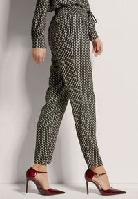 Zwarte broek met een fitted silhouet, versierd met gouden ruitvormen. Gekocht met glanzende rode hoge hakken.