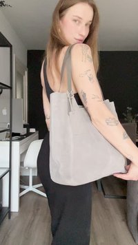 Gray suede tote bag with a soft texture, featuring a minimalist design, adjustable straps, and a secured top closure.