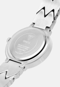 Rustfrit stål ur med en poleret sølvfinish. Har et zigzag-mønsteret rem og en graveret bagside med brand- og vandtætheddetaljer.