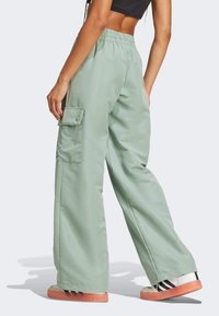 Mintgröna cargobyxor med elastisk midja och sidoficka. Slät, lättviktsmaterial med avslappnad passform och vida ben.