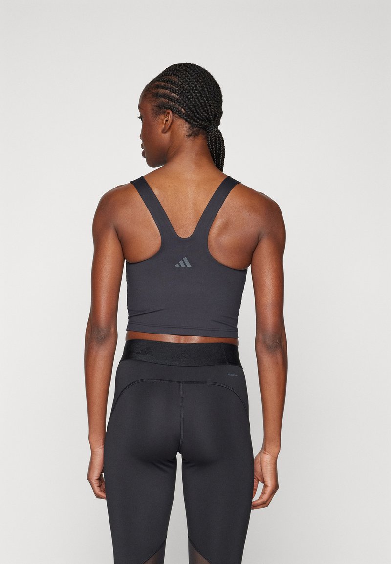 Soutien-gorge de sport noir avec un design dos nageur et un logo subtil. Assorti avec un legging noir taille haute mettant en valeur des accents en maille.