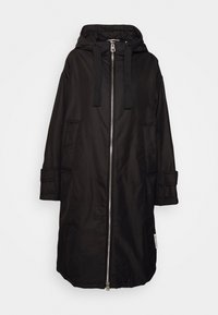 Long manteau noir à capuche avec fermeture éclair avant argentée, capuche avec cordon de serrage, deux poches latérales et sangles réglables aux poignets.