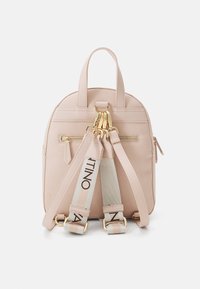 Rosa konstläderryggsäck med guldiga detaljer, topphandtag, justerbara remmar och ficka med dragkedja framtill. Har axelremmar med logotryck.