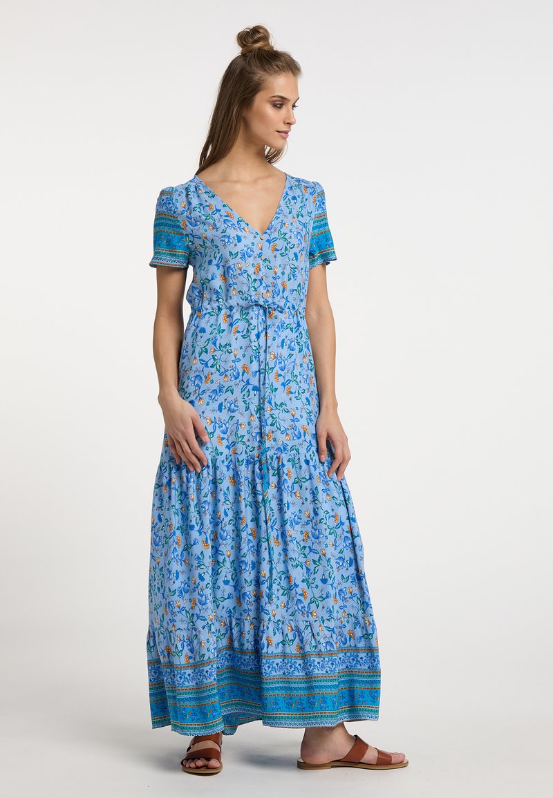Abito lungo realizzato in tessuto azzurro chiaro con stampa floreale. Presenta maniche corte, scollatura a V e orlo a più strati con bordo decorativo nella parte inferiore.