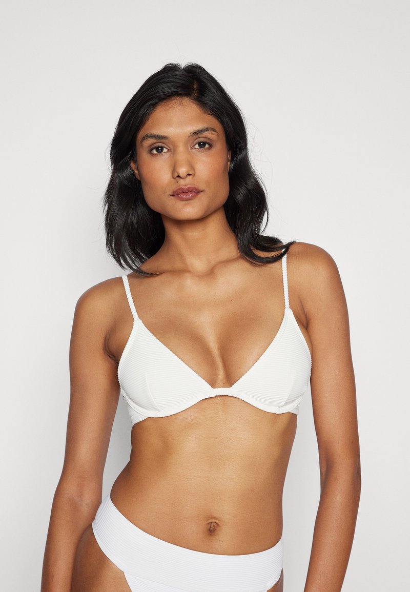 Bílý žebrovaný bikiny top s tenkými nastavitelnými ramínky, s trojúhelníkovým tvarem košíčků a hladkým, bezšvovým designem.