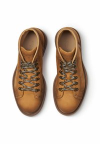 Zapatos de cuero marrón con punteras redondas, cordones de patrón blanco y negro, y una superficie texturizada; interior acolchado y suelas de goma marrón.