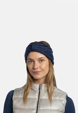 Dark blue knitted headband with a textured pattern and a twist design at the front, worn by a person in a light gray puffer vest.