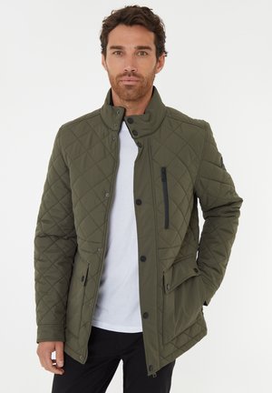 Chaqueta acolchada de color verde oliva con un alto cuello, cierres a presión y un bolsillo con cremallera. Presenta bolsillos laterales y una tela texturizada. Posición: vista frontal.