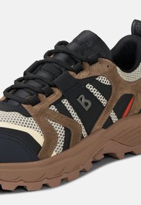 Trail-Sneaker mit einer Mischung aus schwarzem Nylon, braunem Wildleder und Mesh-Elementen, einer robusten braunen Gummisohle und reflektierenden Akzenten.