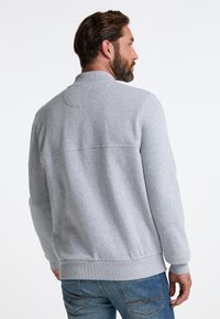 Grå sweatshirt med høj krave, ribstrikkede manchetter og kant. Glat tekstur, lange ærmer og en vandret søm på tværs af ryggen.