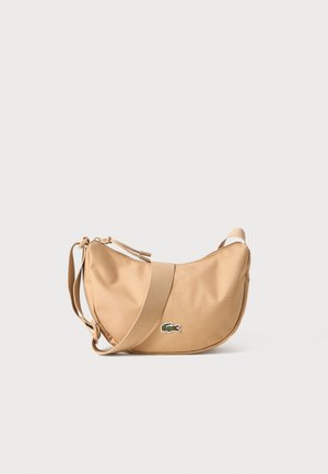 Beige fabric shoulder bag with a rounded design, featuring a textured adjustable strap and a small logo patch. Zipper closure at top.