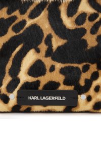 Leopard-print pony hair bag featuring black hardware and a branded black label with silver lettering. Textured surface with varied patterns.