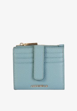 Blauwe leren portemonnee met een gestructureerde afwerking, voorzien van een ritssluiting, verticale kaartsleuven en een gouden "Coccinelle" logo aan de voorkant.