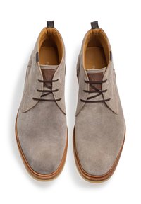 Zapatos de ante grises con cordones marrones, plantilla color beige y suela de goma marrón. Presentan un parche con el logo en la lengüeta y bordes suaves.