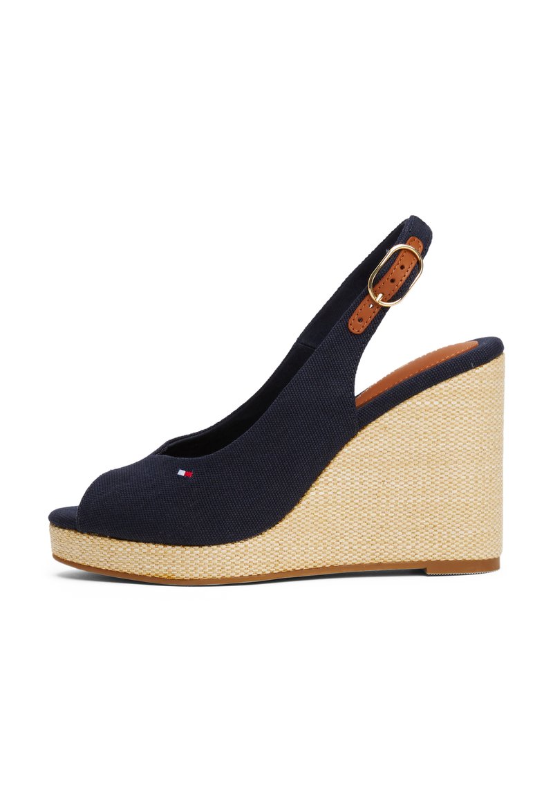 Sandale à talon compensé en toile bleu marine avec un open toe et une plateforme en tissage texturé. Elle présente une sangle en cuir marron avec un accent boucle.