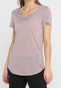 Ljusrosa kortärmad t-shirt i ett mjukt, texturerat tyg, med rundad halsringning och en något böjd slut. 