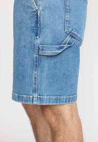 Denim shorts met een lichtblauwe wassing, voorzien van zijzakken, contrasterende stiksels en een rechte snit, eindigend net boven de knie.