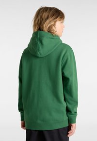 Felpa verde con cappuccio ampio, maniche lunghe e vestibilità rilassata. Texture liscia con polsini e orlo a costine. Design semplice, senza loghi visibili.