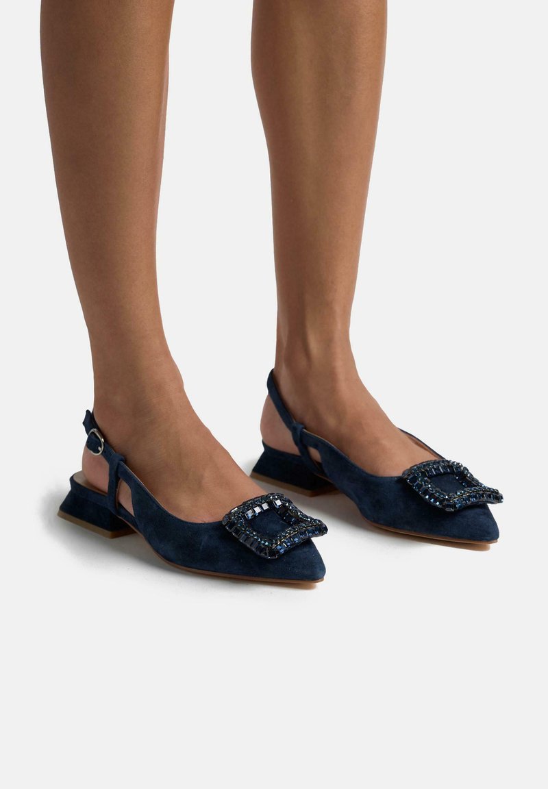 Scarpe slingback in suede blu navy con punta affusolata, dotate di una grande fibbia decorativa adornata con cristalli e un tacco basso a blocco.