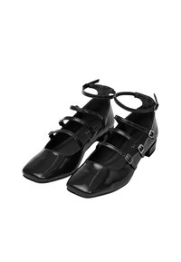 Ballerine in pelle verniciata nera con punta quadrata, dotate di tre cinturini alla caviglia regolabili con fibbie metalliche e tacco basso a blocco.
