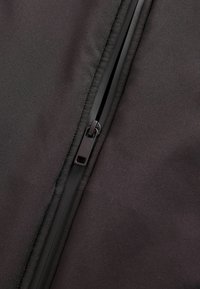 Musta kangas sileda tekstuuriga, millel on tõmblukk, mis kulgeb õmbluse mööda, näidates minimalistlikku disaini ja puhtaid jooni.