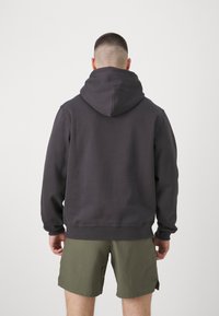 Donkergrijze hoodie met een capuchon, ribbelmanchetten en zoom. Gedoofd over olijfgroene shorts, met een eenvoudig, veelzijdig ontwerp en een zachte textuur.