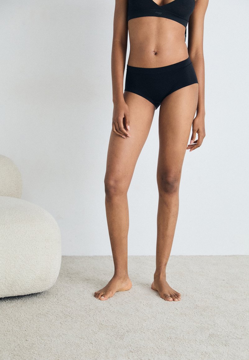 Black seamless bra and matching high-waisted briefs displayed on a model. The fabric appears soft with a smooth texture.