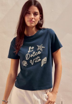 Navy short-sleeve T-shirt with printed text "La Dolce Vita," featuring sparkling starfish and shell designs. Cotton fabric, crew neckline.