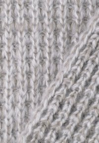 Gebreide stof in zachte grijstinten met een getextureerd ribpatroon. Bevat opvallende dikke en dunne garenstrengen, wat diepte en dimensie creëert.