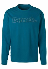 Long-sleeve teal shirt in soft cotton with a round neckline, featuring a large "Bench." graphic in contrasting color on the front.
