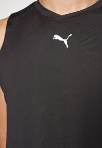 Czarna bezrękawnikowa koszulka sportowa z gładkiego materiału z białym logotypem Puma na klatce piersiowej. Prosty design koncentruje się na funkcjonalności.