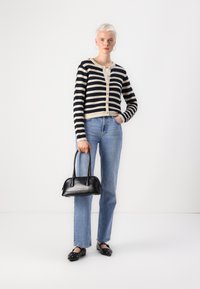 Striped cardigan in navy and cream, buttoned front. Light blue straight jeans. Black patent handbag with short handles, black slip-on shoes.