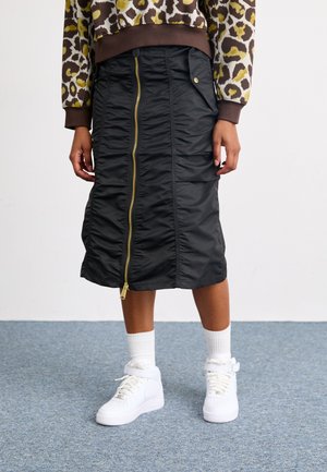 Black midi skirt with gathered texture, gold zipper down the front, and side pockets; worn with white high-top sneakers and white socks.