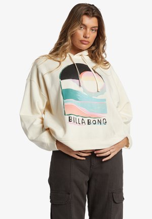 Sudadera color crema con un gráfico frontal que presenta olas abstractas y un sol. Tiene un corte holgado, capucha ajustable y una textura suave.