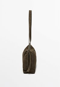 Brown suede bag with a long strap, zip closure, and a tapered design. The texture is soft, complementing the bag's sleek silhouette.