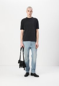 Svart crew-neck t-shirt, ljusblå raka jeans, svarta läderankelboots och en liten svart crossbody-väska. Slät tygtextur.
