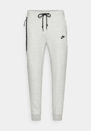 Hellgraue Nike-Sweatpants mit schwarzem Kordelzug, Seitentaschen und Logo. Mit schmal zulaufenden Beinen und gerippten Bündchen. Weicher, strukturierten Stoff.