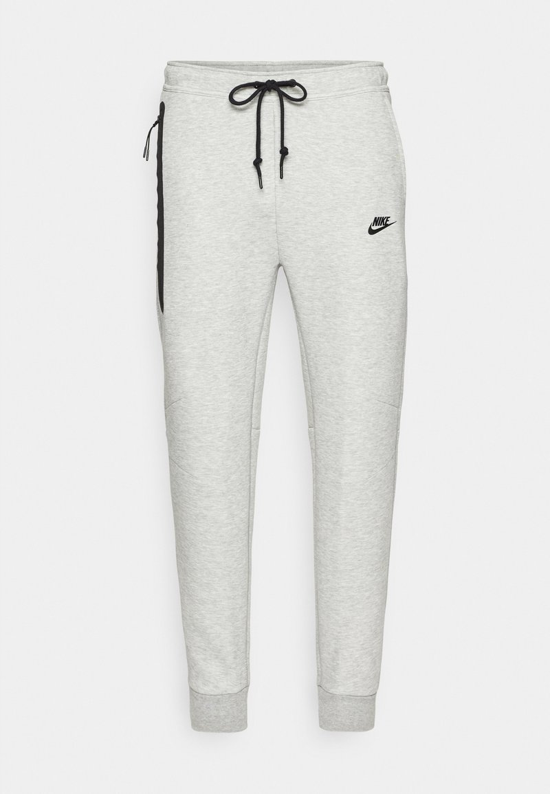 Hellgraue Nike-Sweatpants mit schwarzem Kordelzug, Seitentaschen und Logo. Mit schmal zulaufenden Beinen und gerippten Bündchen. Weicher, strukturierten Stoff.